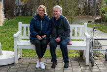 Ein älteres Paar auf einer weißen Bank im Garten
