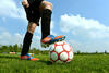 Ein Jugendlicher in Fußballschuhen hat einen Fuß auf einem Fußball.